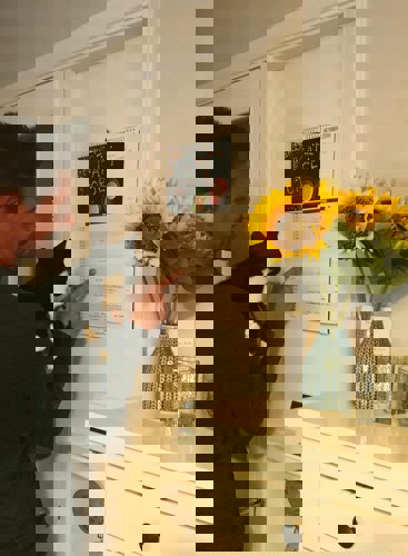 man holding black and white kitten pointing at calendar