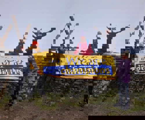 Group of five people standing in front of stone wall holding blue and yellow Cats Protection banner saying 'We are Cat Champions'